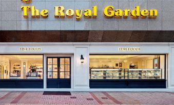 The main entrance of a restaurant features an outdoor view and a sign above it at The Royal Garden Hotel