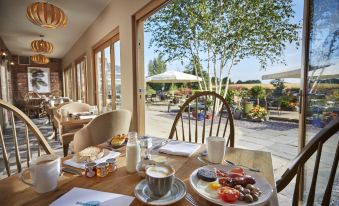 a table is set with breakfast items and drinks , overlooking a dining area with tables and chairs at Lion Quays Resort