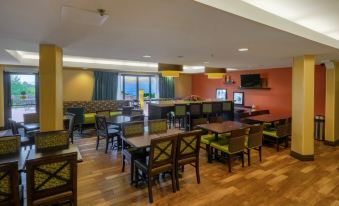 a dining area with wooden tables and chairs , along with a tv mounted on the wall at Hampton Inn Hazleton
