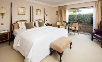 a luxurious bedroom with a large bed , two chairs , and a window overlooking a courtyard at The Atlantic Hotel