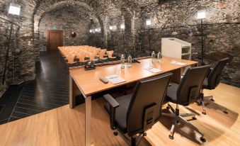 a conference room with a wooden table , chairs , and water bottles , set up for a meeting or presentation at Grand Hotel Della Posta