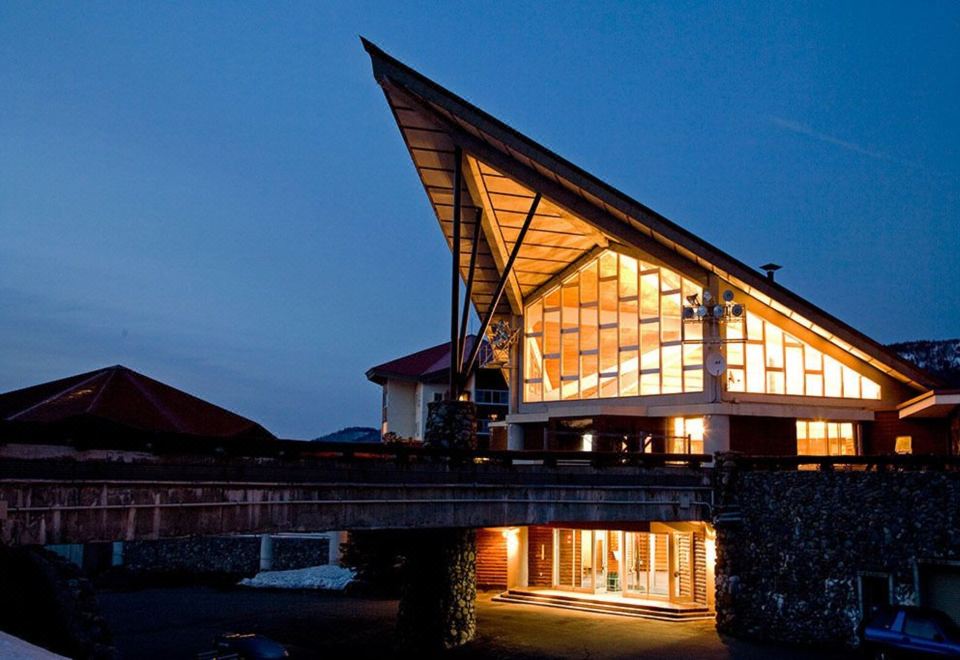 a modern building with a triangular roof and glass windows is lit up at night at Okushiga Kogen Hotel