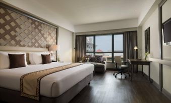 a large , well - made bed is the centerpiece of a hotel room with a view of the city at Melia Purosani Yogyakarta