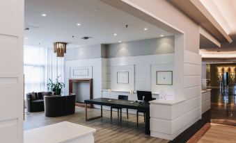 a modern office space with white walls , wooden floors , and black furniture , including a reception desk and chairs at Best Western CTC Hotel Verona