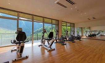 a gym with a row of exercise machines and large windows overlooking a scenic view at Okuhita Onsen Umehibiki