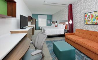 a modern hotel room with a bed , couch , and desk , as well as a living area with a desk and chair at Home2 Suites by Hilton Hagerstown