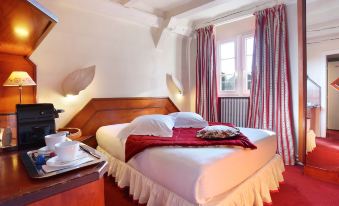 a large bed with white sheets and a red blanket is in a room with wooden furniture at Hotel Suisse