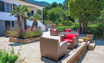 a well - maintained backyard with a variety of outdoor furniture , including chairs and a couch , surrounded by lush greenery at Boutique Hotel Ilio