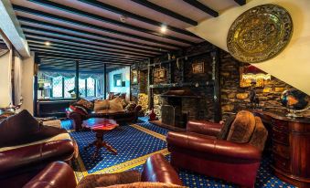 a cozy living room with leather couches and chairs arranged around a fireplace , creating a warm and inviting atmosphere at Damson Dene Hotel