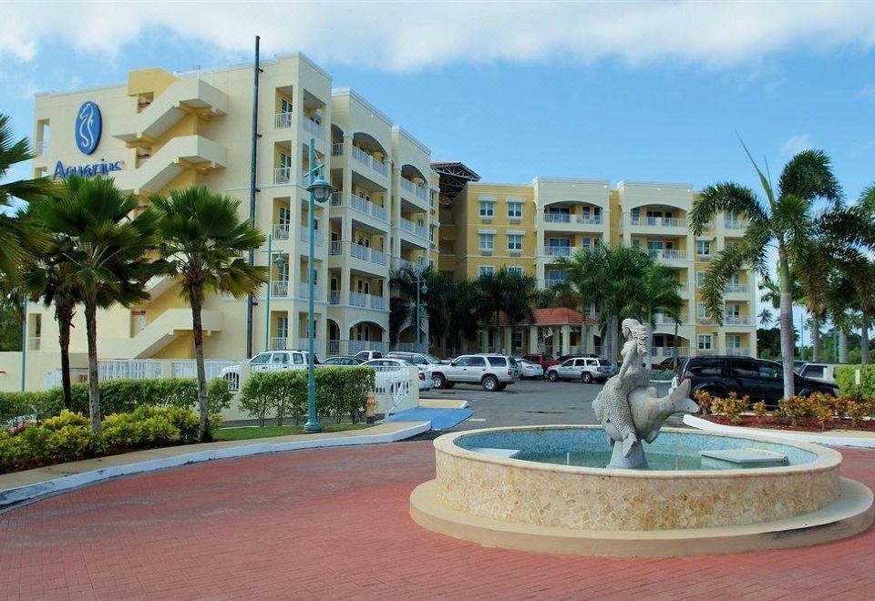 a city street with a fountain in the middle , surrounded by tall buildings and palm trees at Aquarius Vacation Club at Boqueron Beach Resort