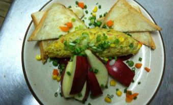 a white plate with a sandwich and vegetables on it , placed on a dining table at Sakol Hotel