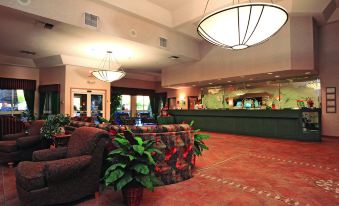 a large hotel lobby with a reception desk , chairs , and potted plants , creating a welcoming atmosphere at Shilo Inn Suites Klamath Falls