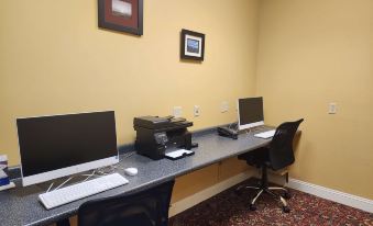 a room with two computer workstations , one on the left and the other on the right , with a printer and printer accessories on the at Best Western White House Inn
