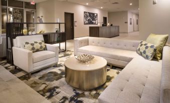 a large , modern hotel lobby with white couches and chairs arranged around a coffee table at Best Western Plus Executive Residency Austin