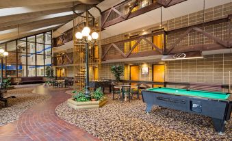 a large hotel lobby with a pool table , a bar area , and several chairs arranged around the tables at Best Western Plus Longbranch Hotel  Convention Center