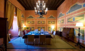 a dining room with a table surrounded by chairs , and a piano placed near the wall at Parador de Jarandilla