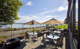 an outdoor dining area overlooking a body of water , with tables and chairs arranged for guests at Red Lion Hotel Port Angeles Harbor