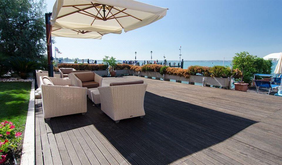 a rooftop terrace with wooden decking , umbrellas , and white wicker furniture , offering a beautiful view of the sea and cityscape at Hotel Eden