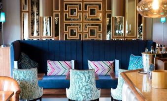 a modern lounge area with blue and white furniture , wooden chairs , and a large geometric wall decoration at Thornton Hall Hotel & Spa
