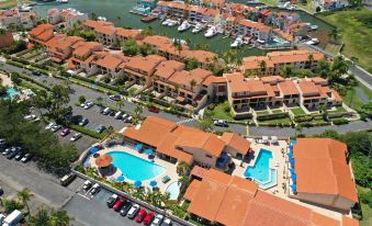 aerial view of a marina with multiple boats docked , buildings , and a swimming pool surrounded by cars at Park Royal Homestay Club Cala Puerto Rico