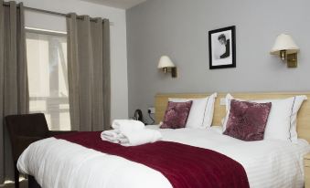 a large bed with a white comforter and red blanket is in a hotel room at Beachcombers Hotel