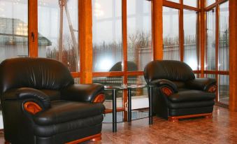 a room with two black leather chairs and a small table in front of a large window at Serebryanyy Bor
