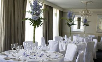 a well - decorated dining room with tables covered in white tablecloths and chairs arranged for a formal event at Chilston Park Hotel