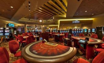 a large , brightly lit casino with multiple tables and chairs , as well as various gambling machines and a roulette table at Sycuan Golf Resort