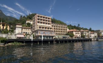 a large building situated on the edge of a body of water , with a boat docked nearby at Hotel Bazzoni