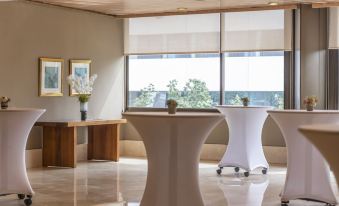 a modern office interior with large windows , white furniture , and a vase of flowers on a table at Hesperia Barcelona Sant Just