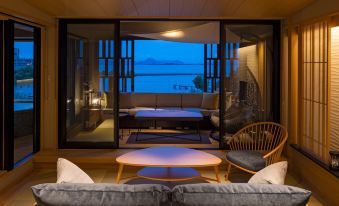 a living room with a couch , chairs , and a table is shown with a view of the ocean through the window at Biwako Ryokusuitei