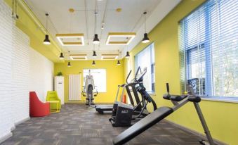There is a centrally located gym with a yellow and green color scheme, as well as an adjacent exercise room at Ibis Styles Hotel (Beijing Capital Airport)