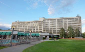 a large white hotel building surrounded by a green field , with trees in the background at DoubleTree by Hilton Hotel Grand Junction