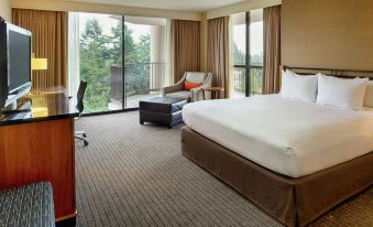 a large bed with a white comforter is in the middle of a room with a desk and chairs at DoubleTree by Hilton Seattle Airport