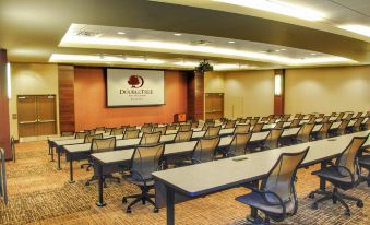 a conference room with rows of tables and chairs , a large screen on the wall , and a logo for dao libre is visible at DoubleTree by Hilton Reading