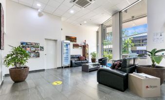a modern living room with a couch , chairs , and a refrigerator in the center of the room at Argus Hotel Darwin