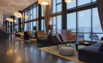 a modern hotel lobby with several couches and chairs arranged in a lounge - like setting , providing seating for guests at Scandic Narvik