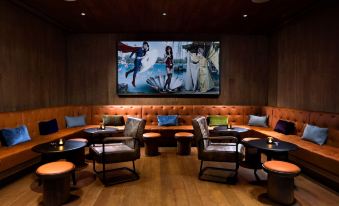 The lounge is equipped with a large screen, leather seats, and tables with built-in screens for watching at EAST Beijing