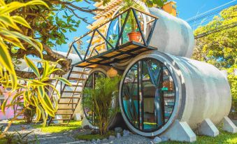 a unique , round - shaped house with a balcony and glass windows is surrounded by lush greenery at Selina Jaco