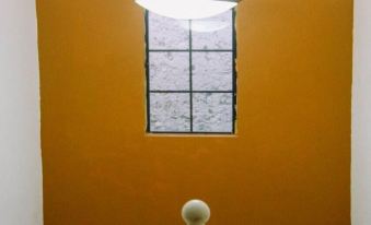 a white chandelier hangs from the ceiling next to an orange wall with a window and a white railing at La Esperanza
