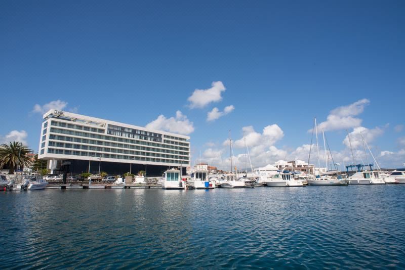 a large white building with a blue awning is surrounded by boats in a harbor at Octant Ponta Delgada