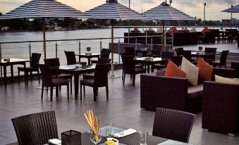 an outdoor dining area with tables and chairs arranged on a patio , overlooking a body of water at Radisson Blu Anchorage Hotel