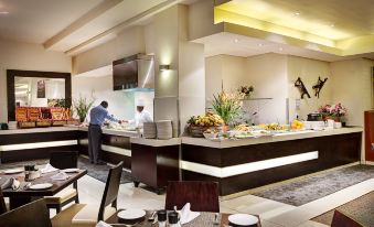 a man is standing at a dining table in a restaurant , preparing food and enjoying his meal at Fountains Hotel