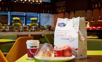 There is a bag of food on the table, and there are two items in front of it at Hampton by Hilton Yiwu International Trade Market
