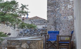 a stone building with a tree in front of it , and two chairs placed on the balcony at Casa Palma