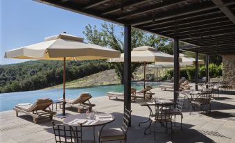 an outdoor patio with a pool surrounded by chairs and umbrellas , creating a relaxing atmosphere at Rosewood Castiglion del Bosco
