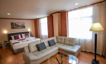 a modern living room with a couch , coffee table , and bed in front of a window at Sakol Hotel