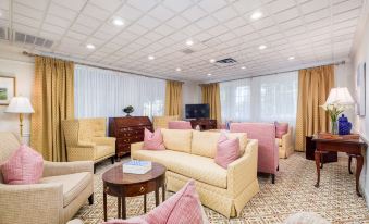 a living room with pink and white furniture , a coffee table , and a tv on the wall at The Farmington Inn and Suites