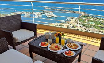 a balcony overlooking a marina , with a dining table set for breakfast and a view of the ocean at Venezuela Marriott Hotel Playa Grande
