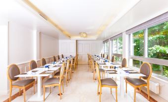 a long dining room with white tables and chairs arranged for a group of people at NH Geneva City